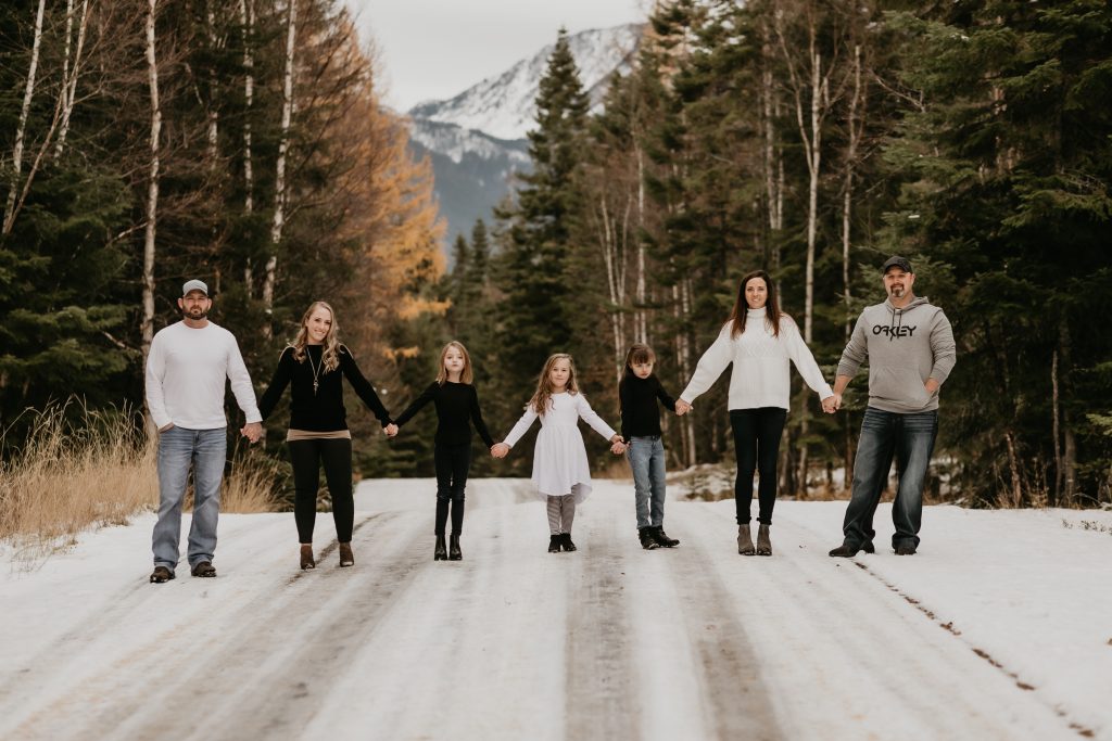 Family poses across snowy road with snow capped mountains in the distance.  Be fearless in pursuit of your dreams